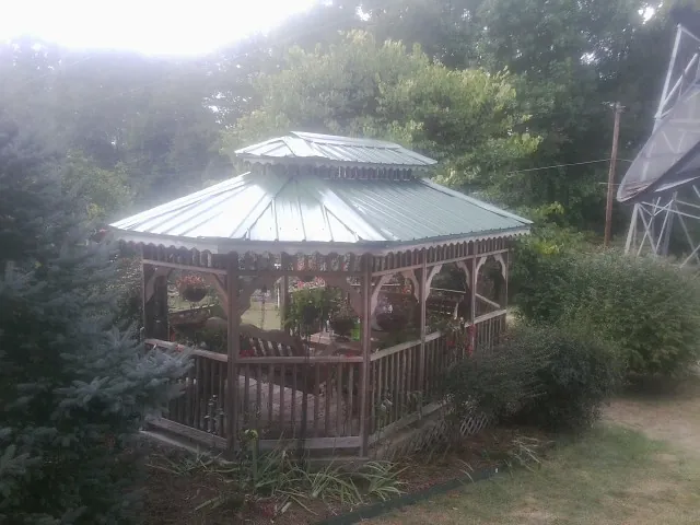 Green metal roof on a backyard gazebo surrounded by garden beds in New Castle